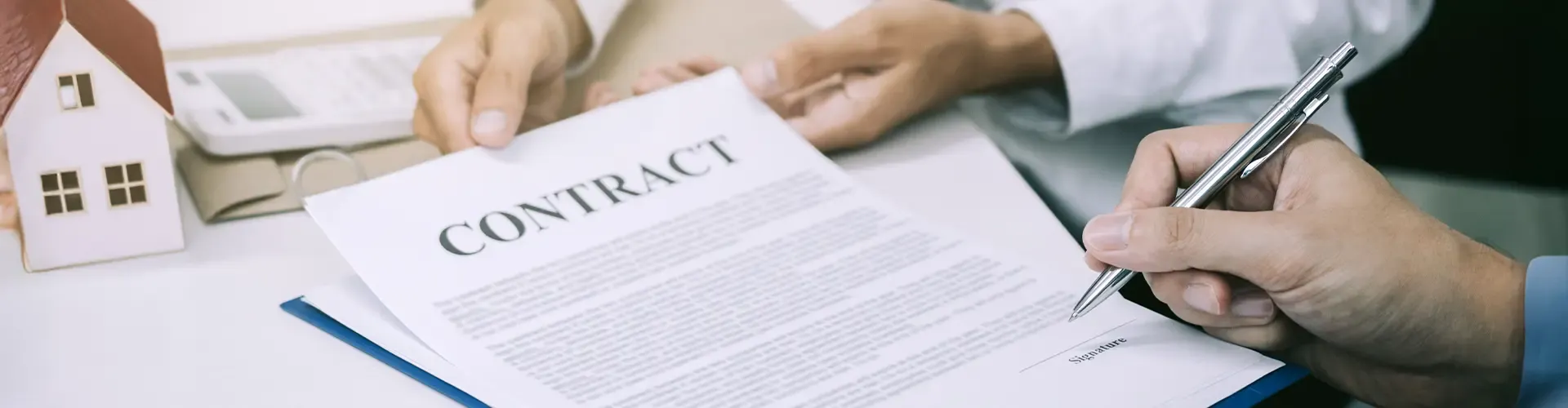 A close-up of a buyer signing a real estate sales agreement, a crucial step in securing an Oqood certificate for a Dubai property.